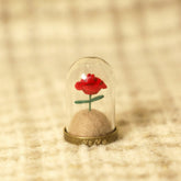 Red rose in a glass dome on a textured beige surface
