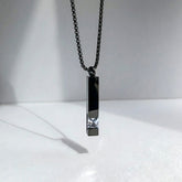 Black pendant necklace with a chain on a white background