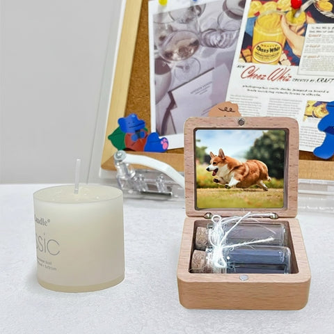Wooden box with a screen displaying a dog, next to a candle on a surface.