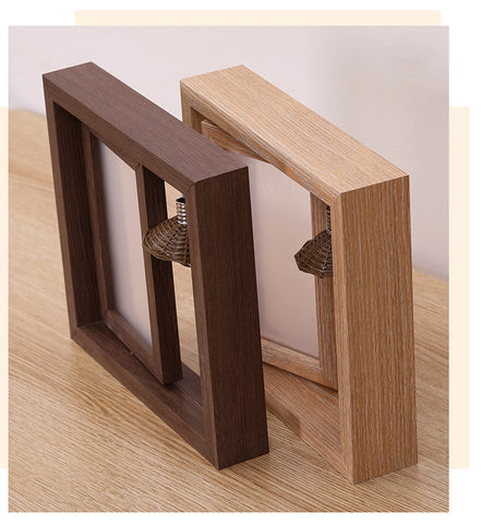 Two wooden picture frames, one brown and one light wood, on a wooden surface.