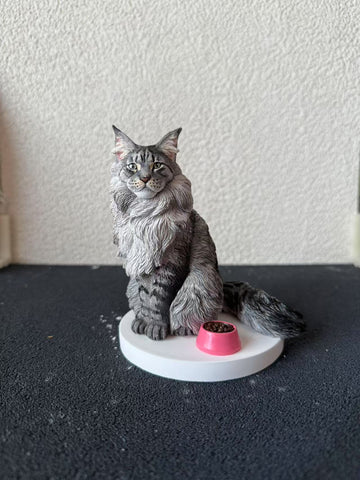 Cat figurine with a pink bowl on a white base against a textured white wall.