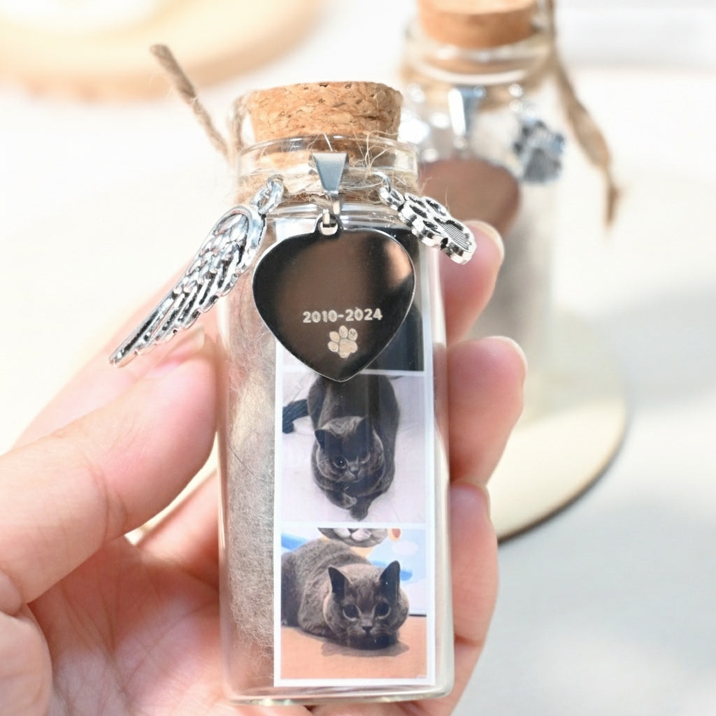 Small glass bottle with cork lid containing a heart-shaped plaque and angel wings charm, held by a hand.