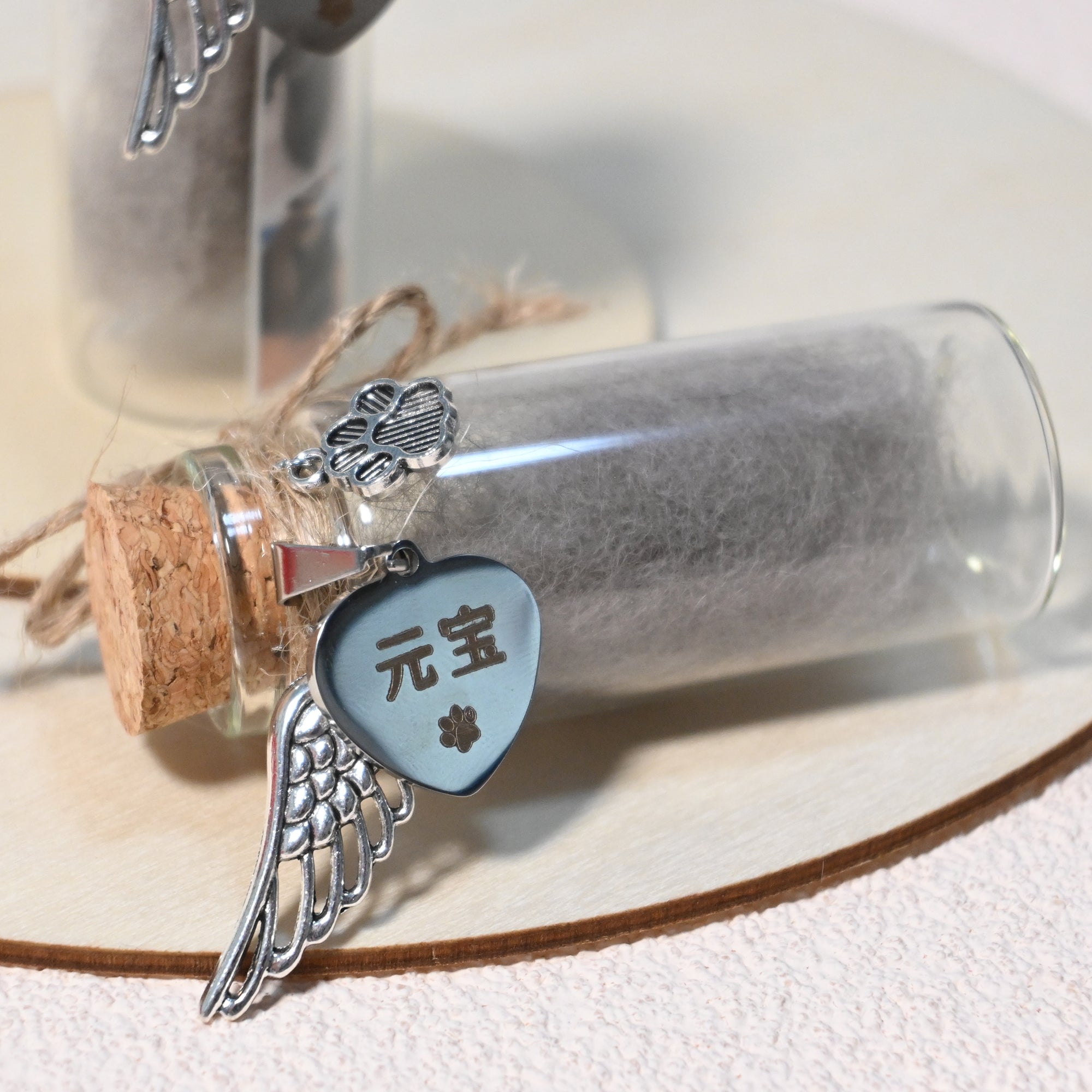 Glass bottle with cork stopper containing charms including a heart-shaped tag with Chinese characters, a wing charm, and a handprint charm.