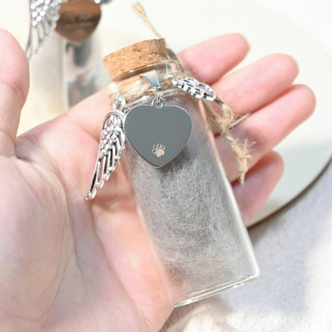 Heart-shaped pendant with wings in a clear bottle held by a hand