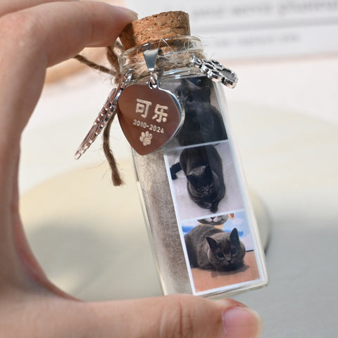 Glass bottle keychain with cork lid, pet tag, and photo of a cat held by a hand.