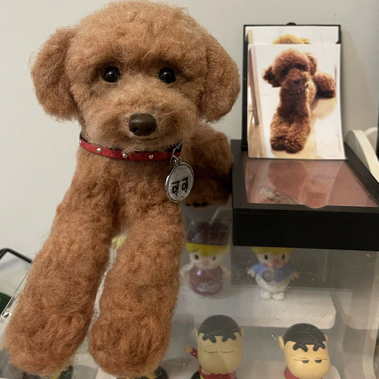 Brown teddy bear with a red collar on a shelf with other small figurines.