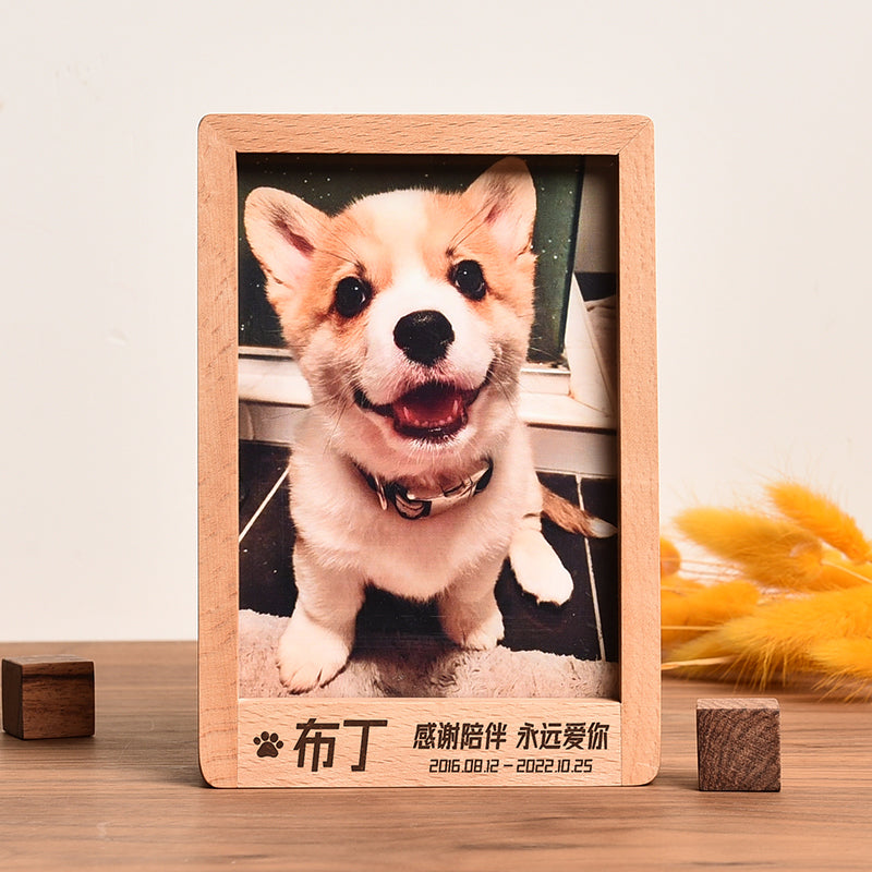 Wooden photo frame with a corgi dog inside on a wooden surface.