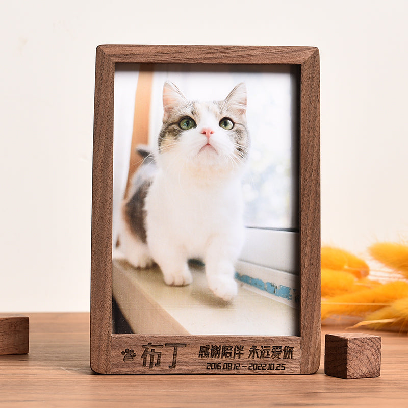 Wooden photo frame with a cat picture and engraved text on a wooden surface.