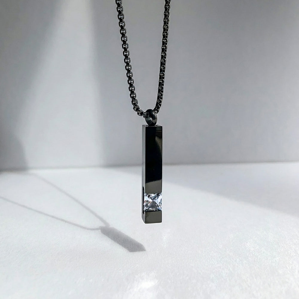 Black pendant necklace with a chain on a white background