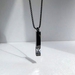 Black pendant necklace with a chain on a white background