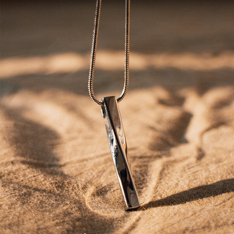 Gold necklace with a pendant on a sandy surface