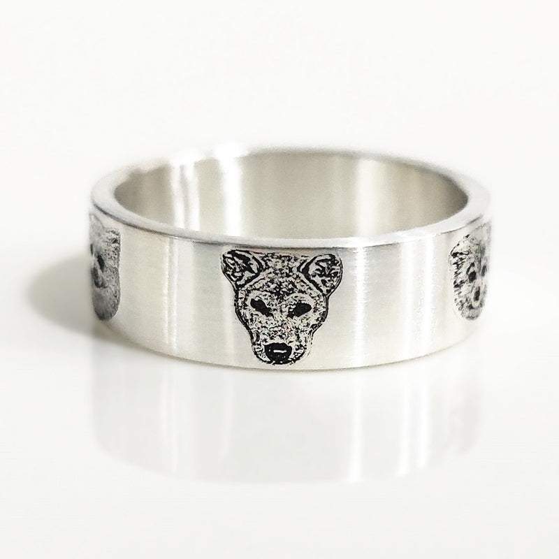 Silver ring with a wolf head design on a white background