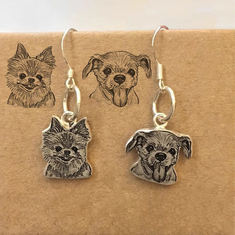 Silver dog-shaped earrings on a cardboard backing with illustrations of dogs.