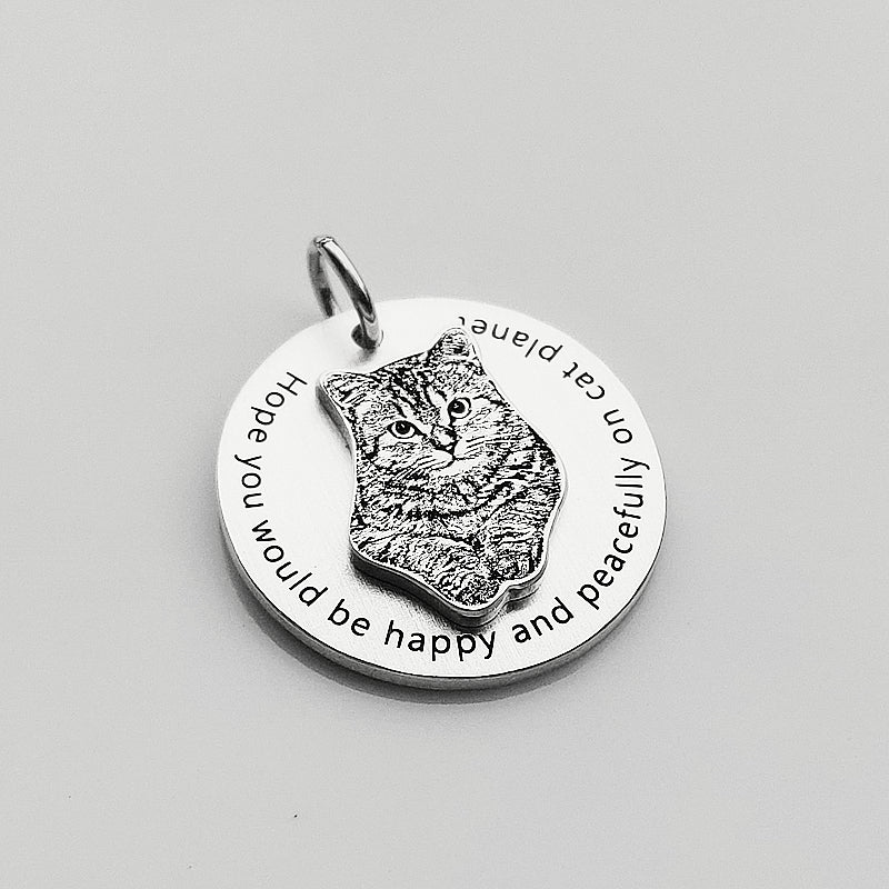 Silver pendant with a cat design and engraved text on a gray background