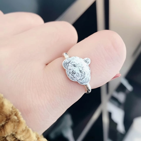 Silver ring with a bear design on a person's finger