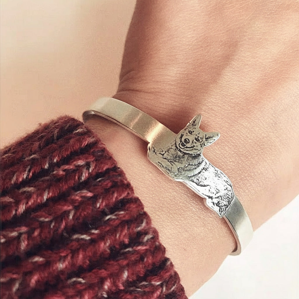Gold and silver bracelet on a wrist with a red knitted sleeve.