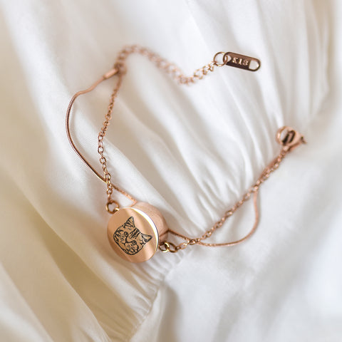 Gold bracelet with a cat face charm on a white fabric background