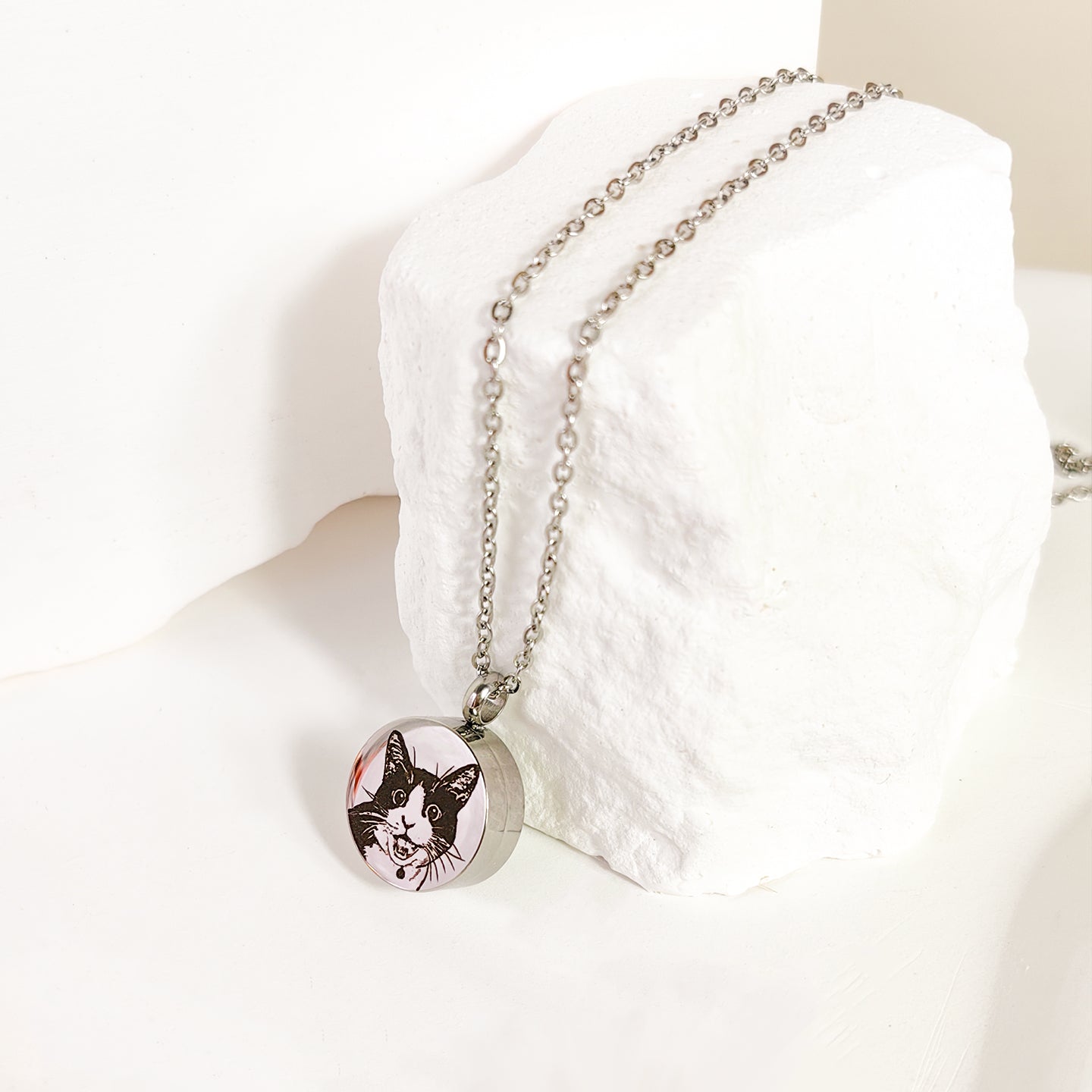 Necklace with a pendant featuring a cat's face on a white cushion