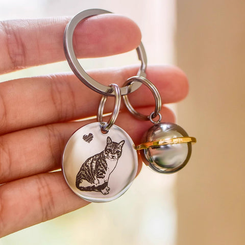Keychain with a cat design held in a hand against a blurred background