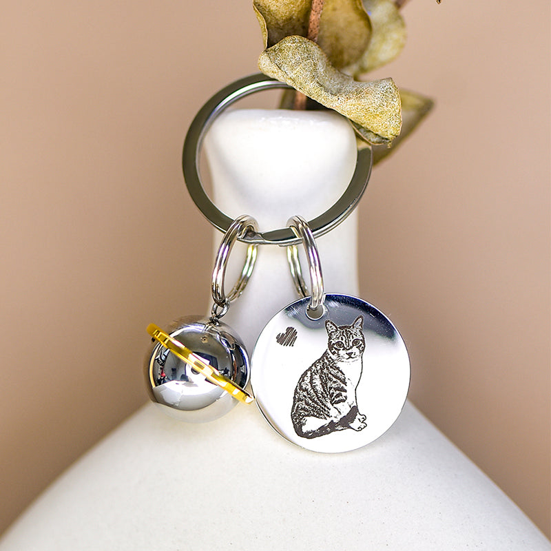 Silver keychain with a cat design on a white surface