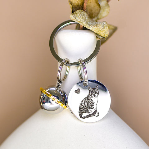 Silver keychain with a cat design on a white surface