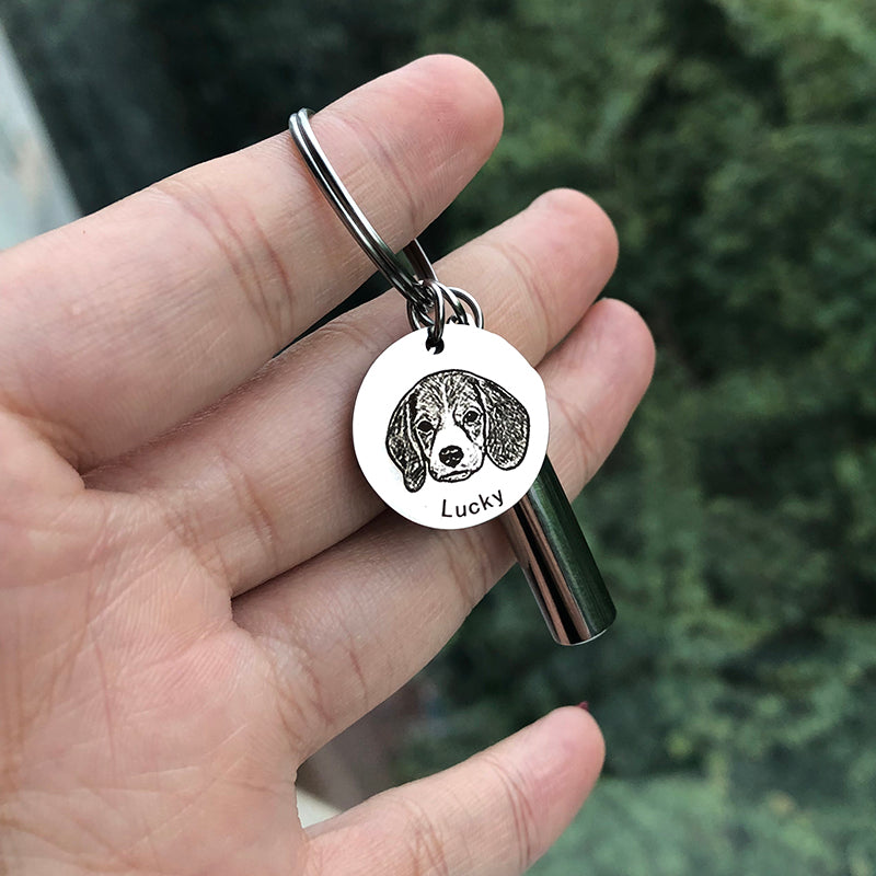Keychain with a dog tag featuring a dog's face and the name 'Lucky' held in a hand against a blurred green background.