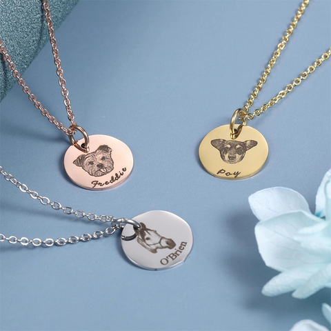 Three necklaces with dog pendants and engraved names on a blue background