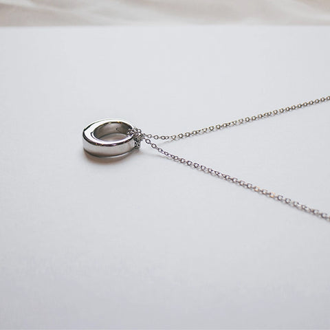 Silver necklace with a round pendant on a light gray background