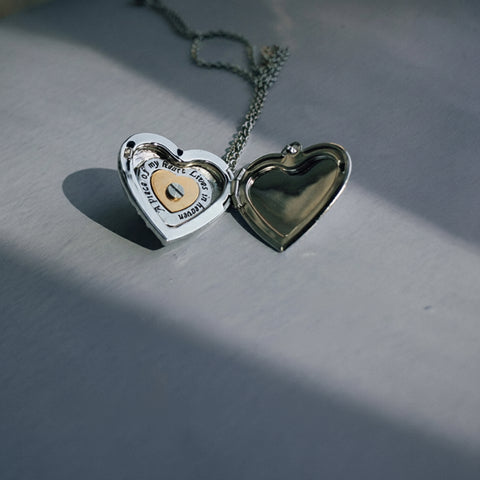 Heart-shaped locket on a chain against a gray background