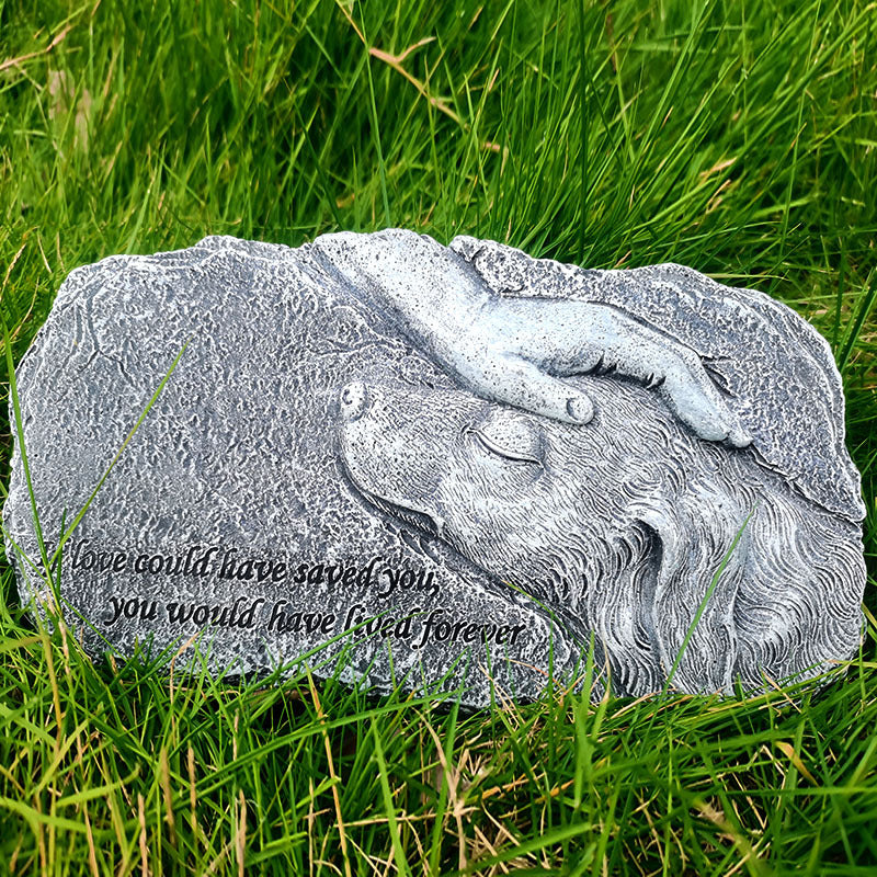 Stone sculpture of a dog lying down with a hand on its head, set against a grassy background.
