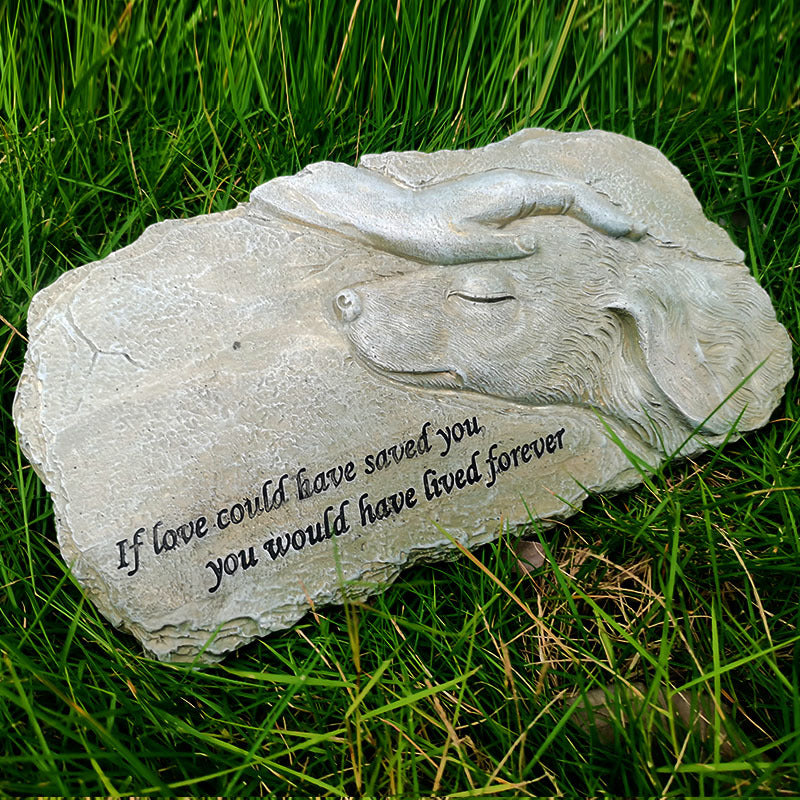 Stone sculpture of a dog and cat with engraved text on grass