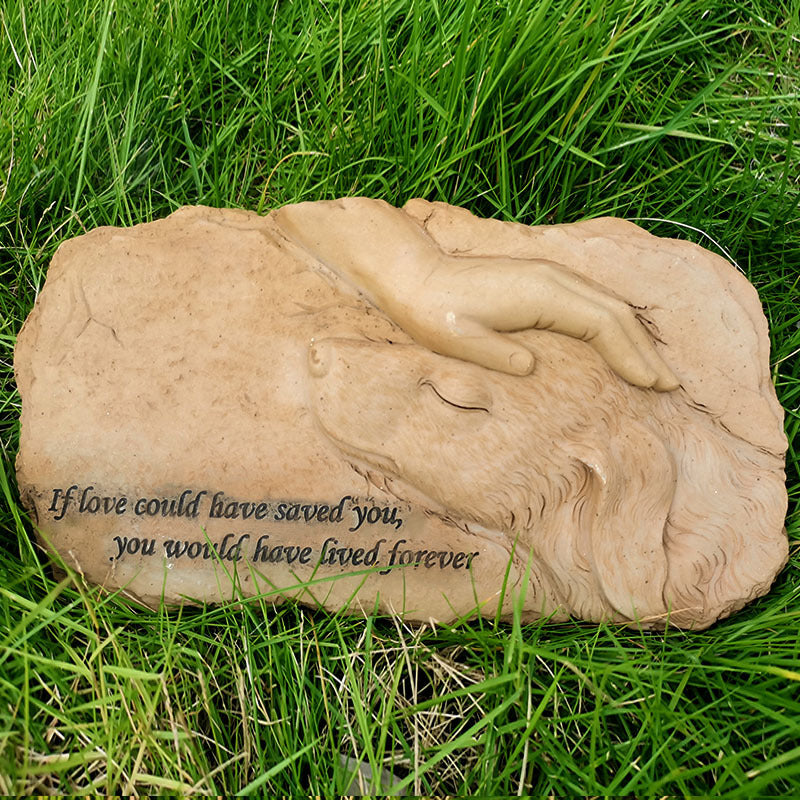 Stone sculpture of a couple embracing on grass with a quote.