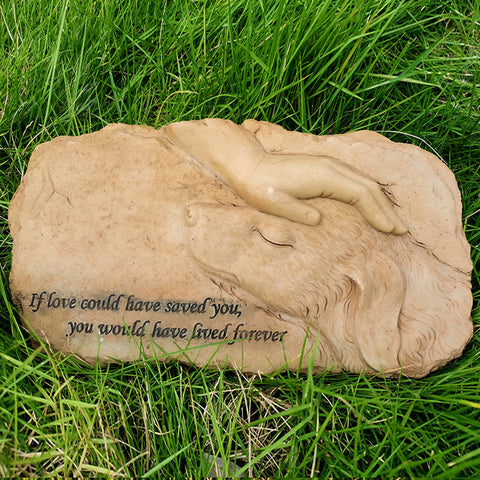 Stone sculpture of a couple embracing on grass with a quote.