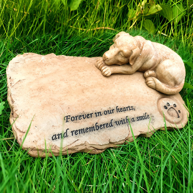 Memorial stone with a dog sculpture and engraved text on grass