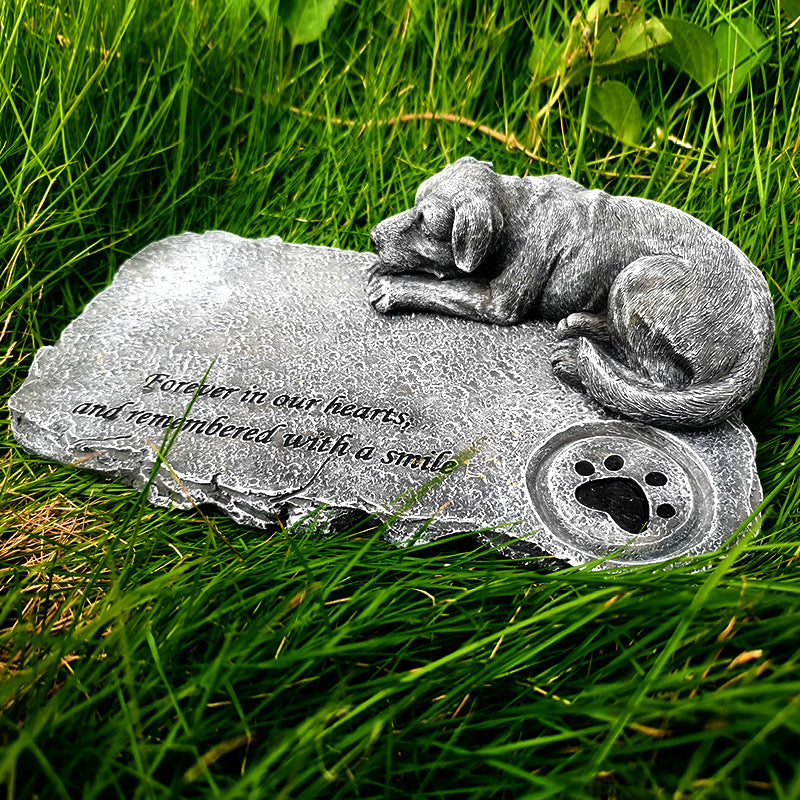 Memorial stone with a dog sculpture and engraved text on grass