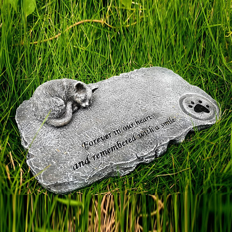 Memorial stone with a cat design and engraved text on grass