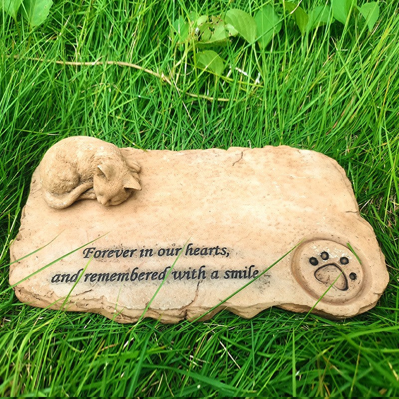 Memorial stone for pets with text 'Forever in our hearts, and remembered with a smile' on grass.