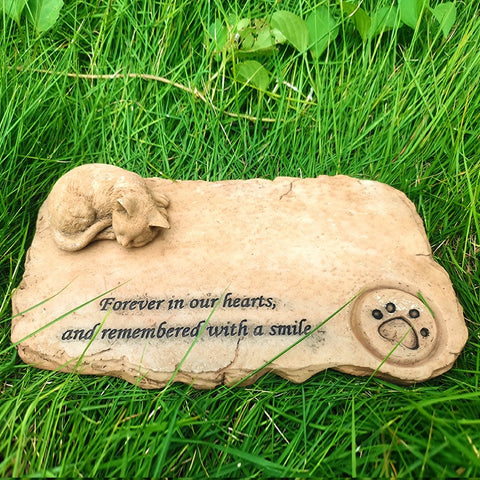 Memorial stone for pets with text 'Forever in our hearts, and remembered with a smile' on grass.