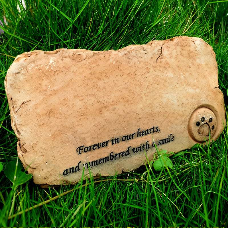 Memorial stone with text 'Forever in our hearts, and remembered with a smile' on grass