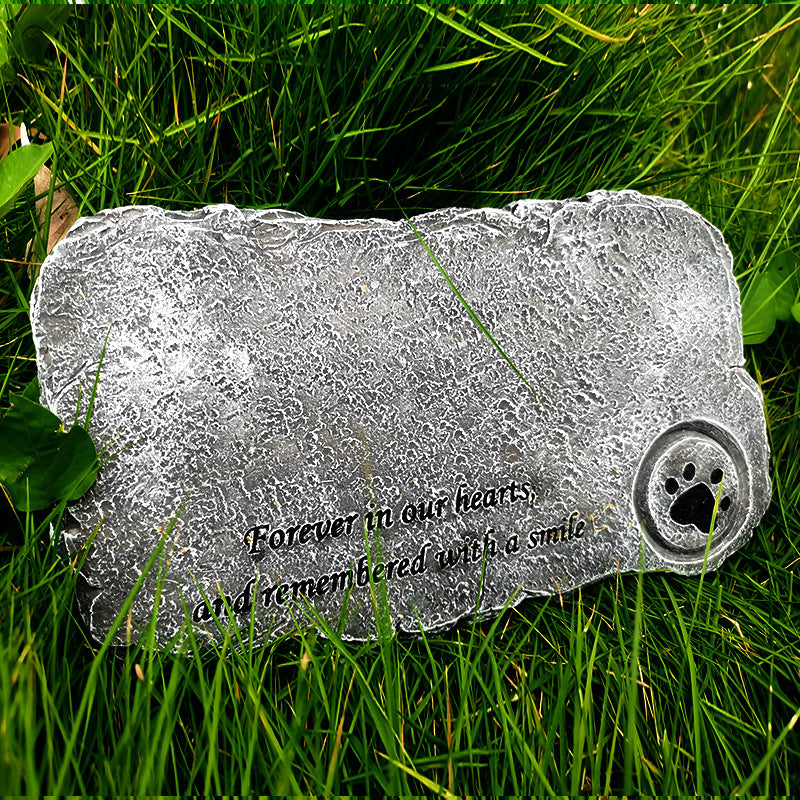 Memorial stone with engraved text and paw print on grass