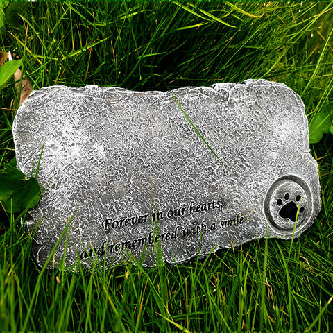 Memorial stone with engraved text and paw print on grass