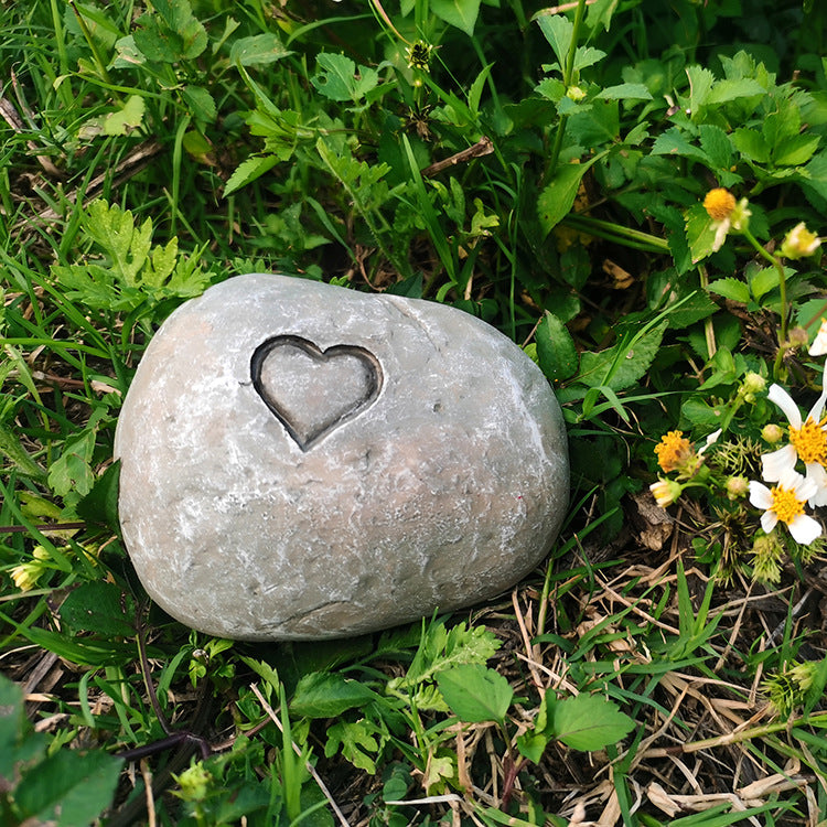 Gray stone with a heart-shaped depression on a grassy background
