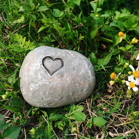Gray stone with a heart-shaped depression on a grassy background