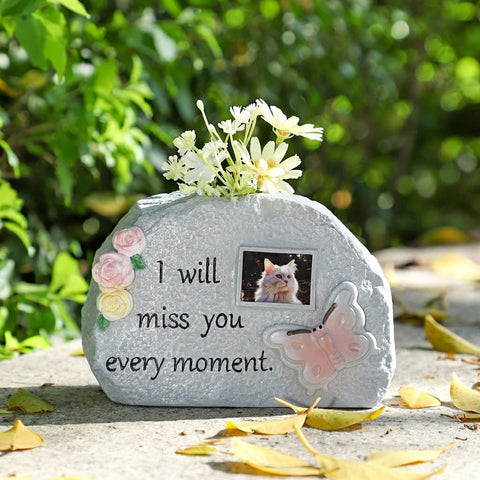 Memorial stone with flowers, butterfly, and photo of a cat with text 'I will miss you every moment.'