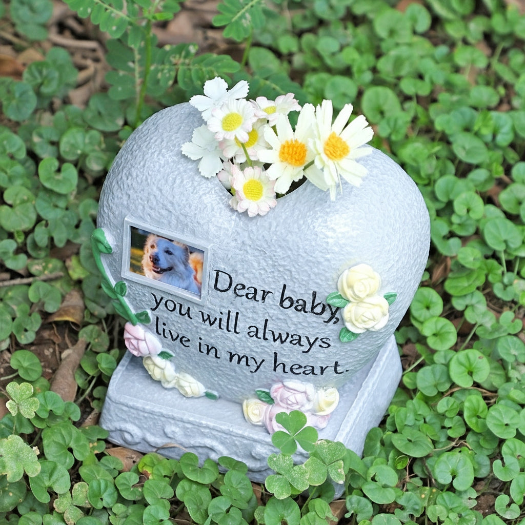 Heart-shaped memorial stone with flowers and a photo of a dog on a grassy background