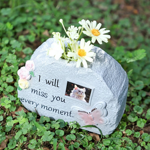 Memorial stone with flowers and a photo of a cat on a grassy background