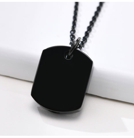Black dog tag pendant on a chain against a white background