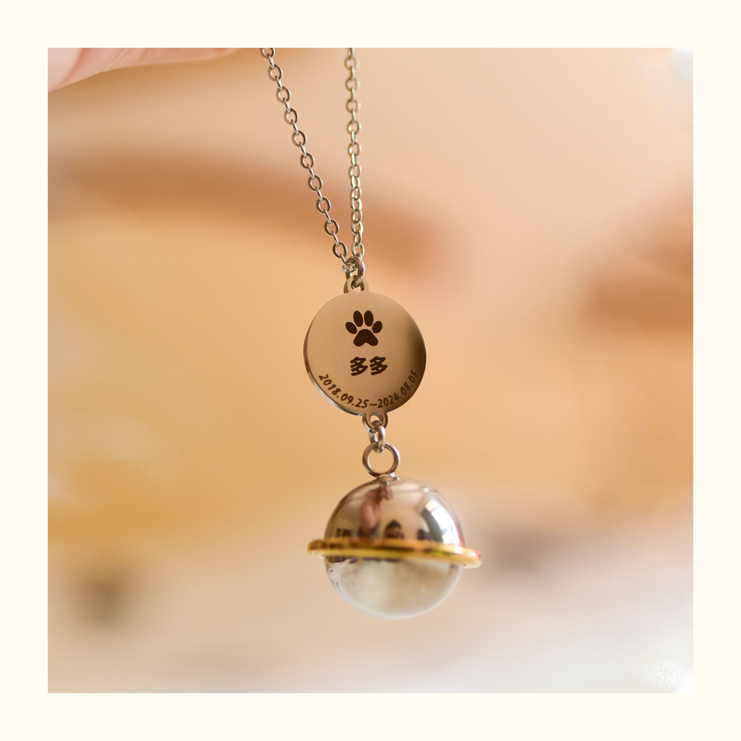 Necklace with a glass sphere and paw print pendant on a blurred background