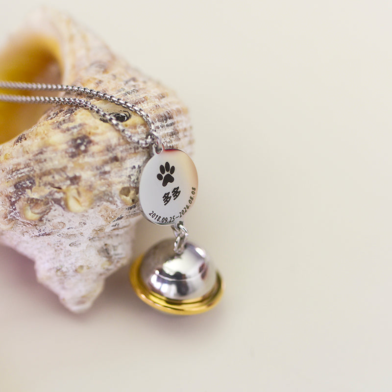 Necklace with paw print charm and bell on a shell background