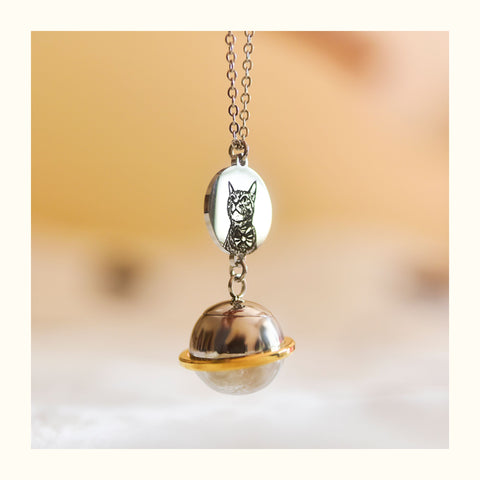 Silver necklace with a round pendant featuring a cat design on a blurred background